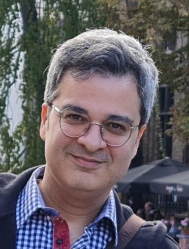 Dr. Amir Masoumi headshot, man with glasses and plaid shirt smiling